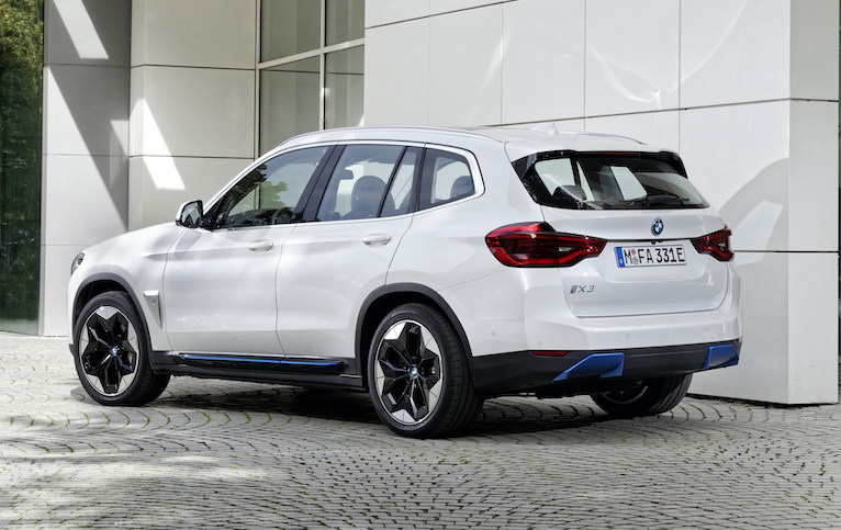 BMW iX3 exterior rear and side parked in front of building