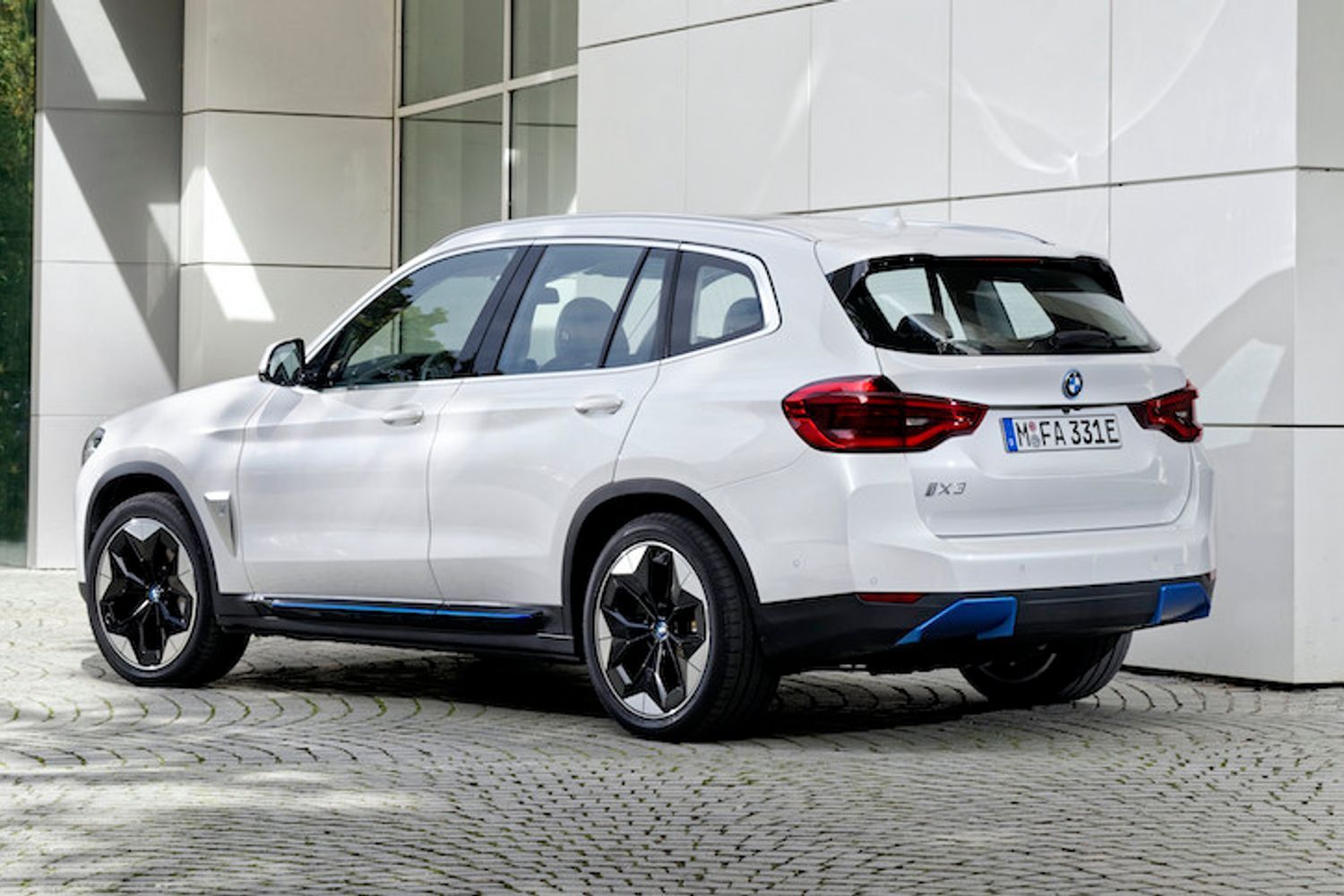 BMW iX3 exterior rear and side parked in front of building