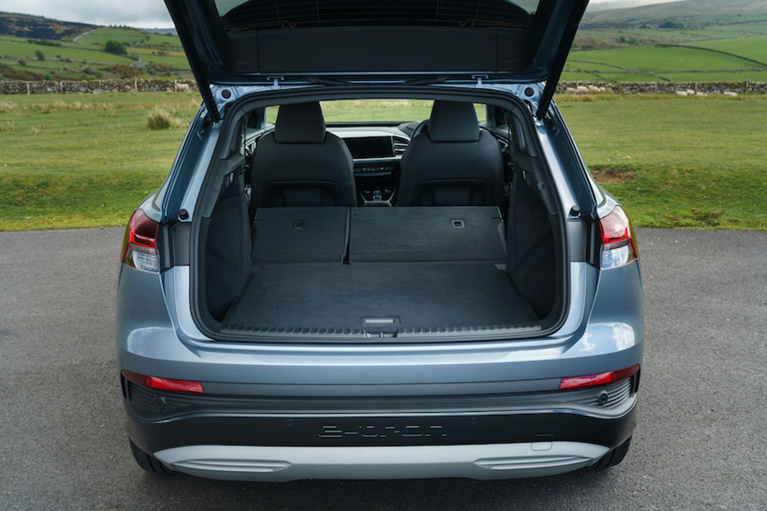 Audi Q4 e-tron boot space showing seats folded, blue/silver car, RHD