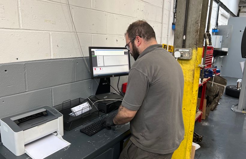 MoT tester entering details into a computer in workshop